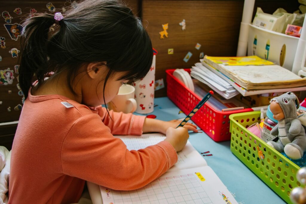 little girl sitting at a desk writing in a book