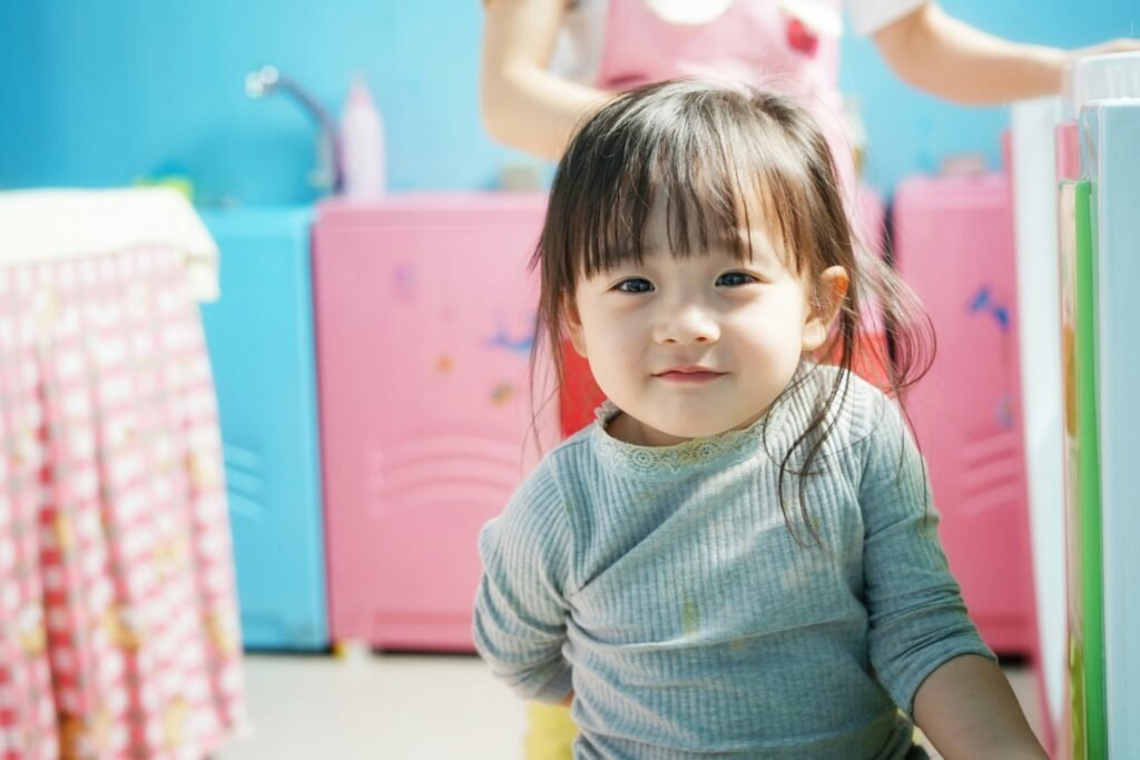 little girl staring at the camera sitting in a play kitchen