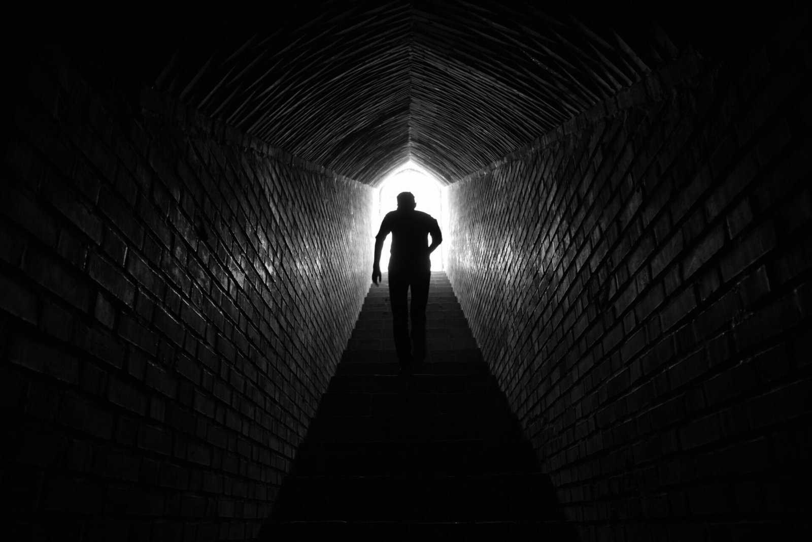 silhouette of person climbing stairs in a dark tunnel